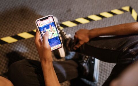 A person playing a colorful puzzle game on a smartphone while seated indoors.