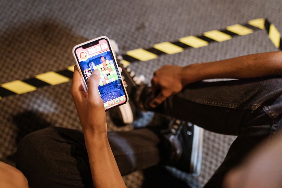 A person playing a colorful puzzle game on a smartphone while seated indoors.