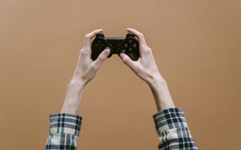Close-up of hands holding a game controller against a brown background, perfect for gaming themes.