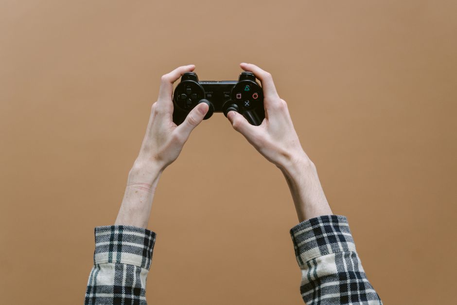 Close-up of hands holding a game controller against a brown background, perfect for gaming themes.