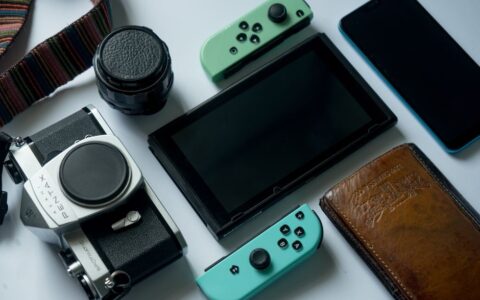 A composition of modern gadgets including a gaming console, smartphone, and a retro camera.