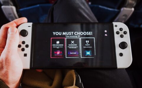 Close-up of a person holding a gaming console with an on-screen decision prompt.