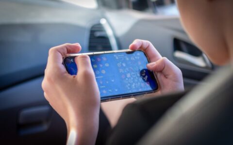 A teenager plays a mobile game while sitting inside a car, showcasing modern technology engagement.