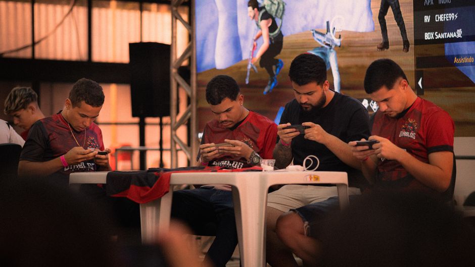 Group of gamers intensely focused during a mobile e-sports tournament indoors.