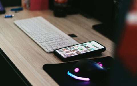 A sleek desktop setup featuring a smartphone, keyboard, and vibrant RGB mouse.